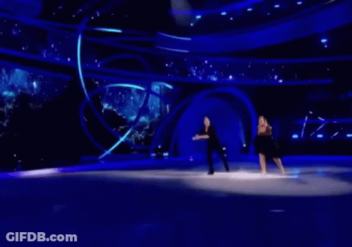 A Man And A Woman Are Ice Skating On A Stage GIF