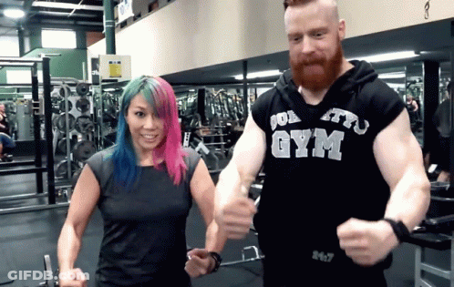 A Man And A Woman Are In A Gym And The Man Is Wearing A Gym Hoodie GIF