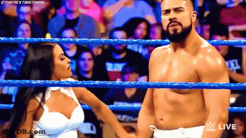 A Man And A Woman Are In A Wrestling Ring Holding Hands . GIF