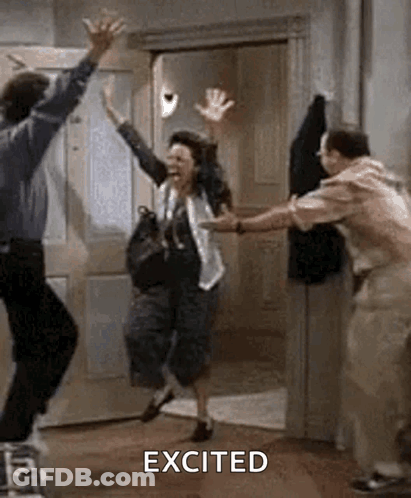 A Man And A Woman Are Jumping In The Air In A Room With Their Arms In The Air . GIF