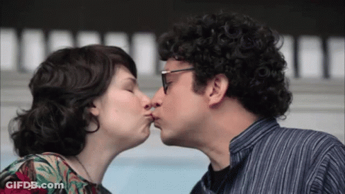 A Man And A Woman Are Kissing And The Man Is Wearing Glasses GIF