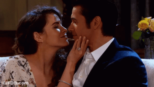 A Man And A Woman Are Kissing And The Woman Has A Diamond Ring On Her Finger GIF