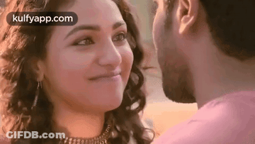 A Man And A Woman Are Kissing Each Other And The Woman Is Smiling . GIF