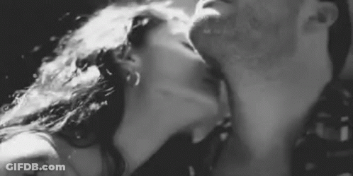 A Man And A Woman Are Kissing Each Other In A Black And White Photo . GIF