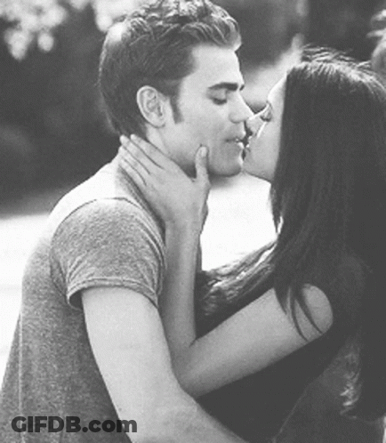 A Man And A Woman Are Kissing Each Other In A Black And White Photo . GIF
