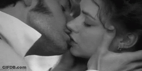 A Man And A Woman Are Kissing Each Other In A Black And White Photo . GIF
