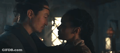 A Man And A Woman Are Kissing Each Other In A Dark Room . GIF