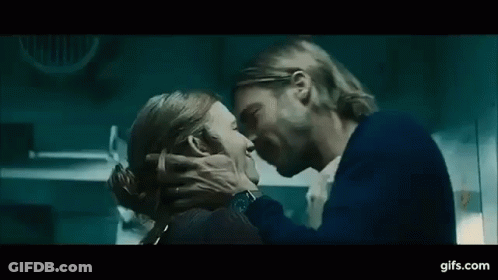 A Man And A Woman Are Kissing Each Other In A Dark Room . GIF