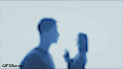 A Man And A Woman Are Kissing Each Other In A Dark Room . GIF