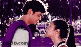 A Man And A Woman Are Kissing Each Other In A Park . GIF