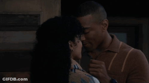 A Man And A Woman Are Kissing Each Other In Front Of A Door . GIF