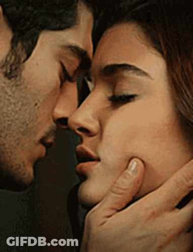 A Man And A Woman Are Kissing Each Other On The Cheek . GIF