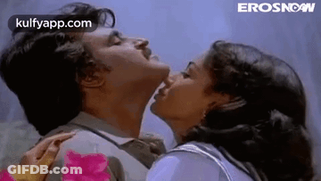 A Man And A Woman Are Kissing Each Other On The Cheek . GIF