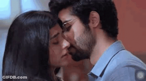 A Man And A Woman Are Kissing Each Other On The Cheek . GIF