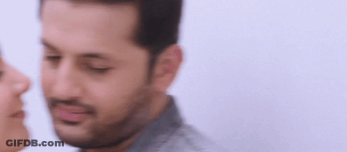A Man And A Woman Are Kissing Each Other On The Cheek . GIF