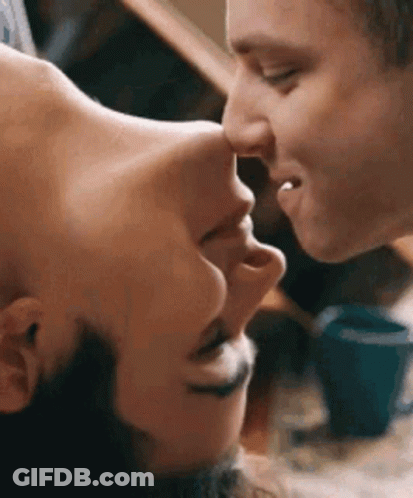 A Man And A Woman Are Kissing Each Other On The Forehead . GIF