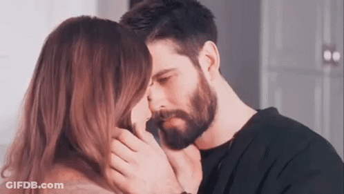 A Man And A Woman Are Kissing Each Other . The Man Has A Beard And The Woman Has Long Hair . GIF