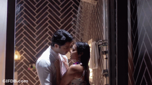 A Man And A Woman Are Kissing In A Bathroom GIF