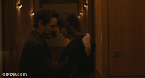 A Man And A Woman Are Kissing In A Dark Hallway GIF