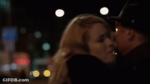 A Man And A Woman Are Kissing In A Dark Room . The Woman Is Wearing A Hat . GIF