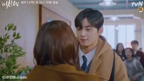 A Man And A Woman Are Kissing In A Hallway . GIF