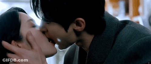 A Man And A Woman Are Kissing In A Room . GIF