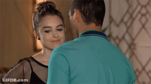 A Man And A Woman Are Kissing In A Room . The Woman Is Wearing A Black Top . GIF
