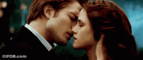 A Man And A Woman Are Kissing In Front Of A Blue Sky . GIF