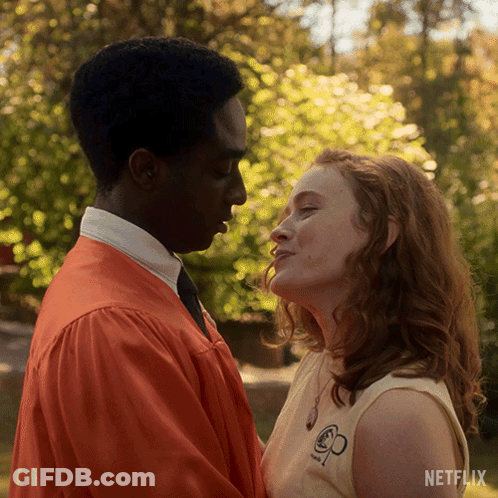 A Man And A Woman Are Kissing In Front Of A Netflix Ad GIF