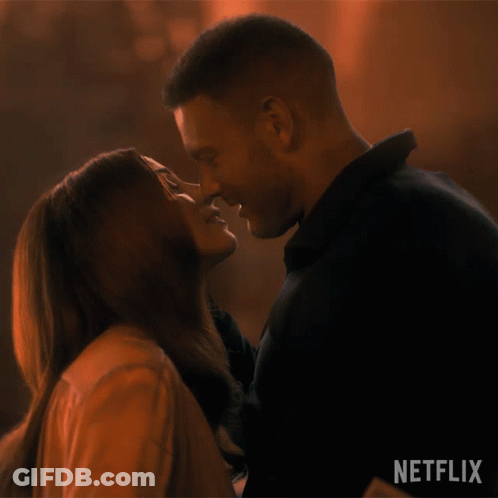 A Man And A Woman Are Kissing In Front Of A Netflix Logo GIF