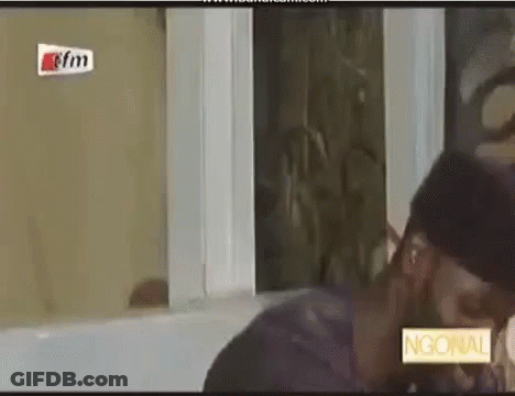 A Man And A Woman Are Kissing In Front Of A Window In A Room . GIF