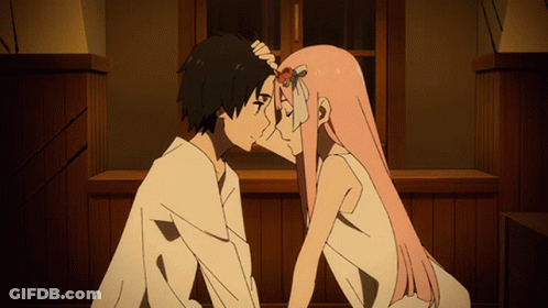 A Man And A Woman Are Kissing In Front Of A Wooden Wall GIF