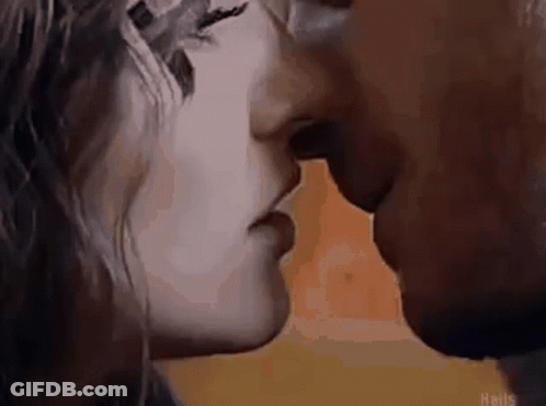 A Man And A Woman Are Kissing In Front Of A Yellow Background . GIF