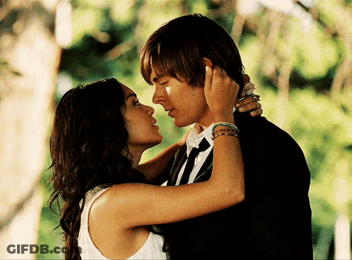 A Man And A Woman Are Kissing In Front Of Trees GIF