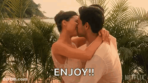 A Man And A Woman Are Kissing On A Beach . GIF