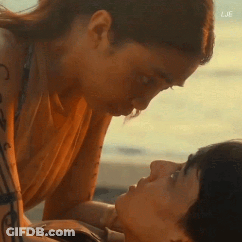 A Man And A Woman Are Kissing On The Beach With The Letters Lje On The Bottom GIF