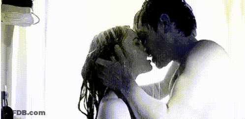 A Man And A Woman Are Kissing Under A Shower . GIF