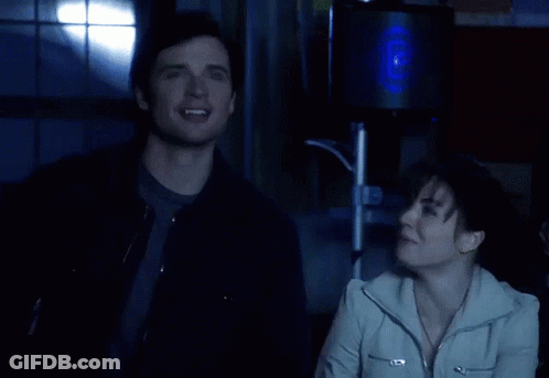 A Man And A Woman Are Laughing In Front Of A Speaker GIF