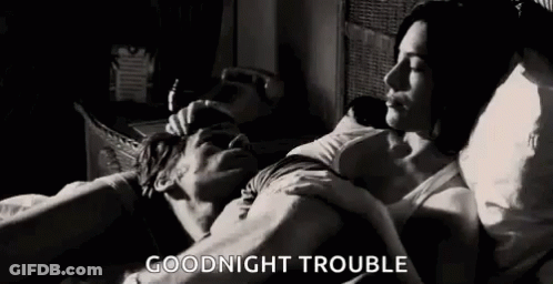 A Man And A Woman Are Laying In Bed And The Man Is Kissing The Woman On The Forehead . GIF