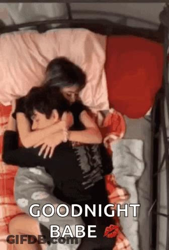 A Man And A Woman Are Laying In Bed Hugging Each Other . GIF