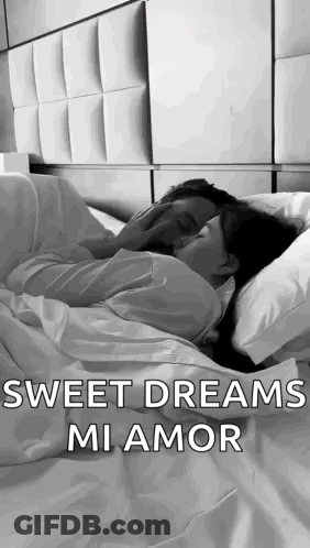 A Man And A Woman Are Laying In Bed Kissing . GIF