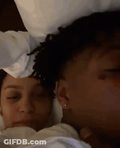 A Man And A Woman Are Laying In Bed With Their Eyes Closed . The Woman Is Wearing Earrings . GIF