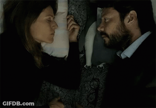 A Man And A Woman Are Laying Next To Each Other And Touching Their Noses GIF