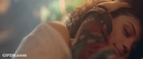 A Man And A Woman Are Laying Next To Each Other In Bed . GIF