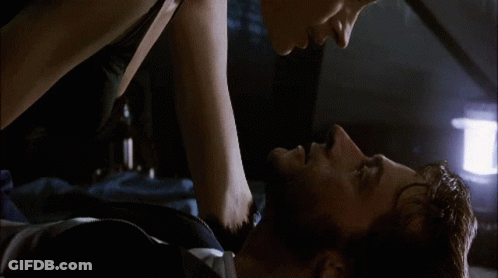 A Man And A Woman Are Laying On A Bed And Kissing GIF