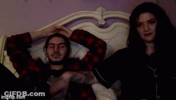 A Man And A Woman Are Laying On A Bed And The Man Has A Tattoo On His Arm GIF