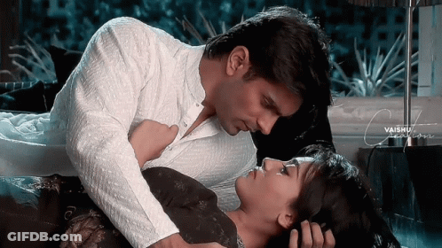 A Man And A Woman Are Laying On A Bed And The Man Is Kissing The Woman On The Forehead GIF
