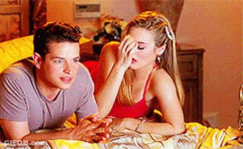 A Man And A Woman Are Laying On A Bed And The Woman Is Covering Her Face With Her Hand GIF
