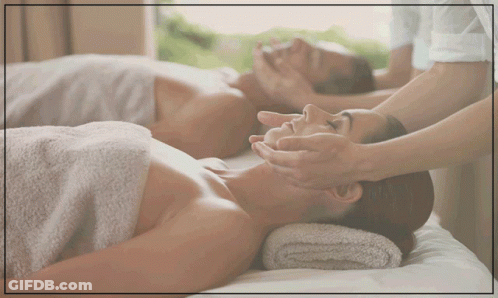 A Man And A Woman Are Laying On A Bed Getting A Massage GIF