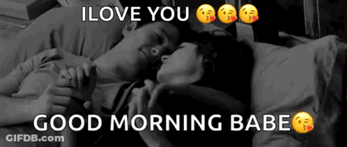 A Man And A Woman Are Laying On A Bed Holding Hands . GIF